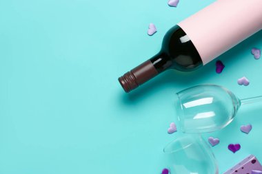 Bottle of wine, glasses and hearts on turquoise background. Valentine's Day celebration