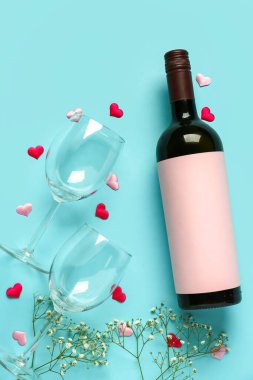 Bottle of wine, glasses and flowers on turquoise background. Valentine's Day celebration