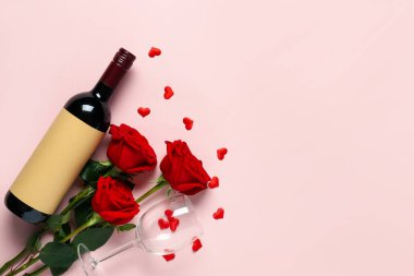 Bottle of wine with red roses and glass on pink background. Valentine's Day celebration