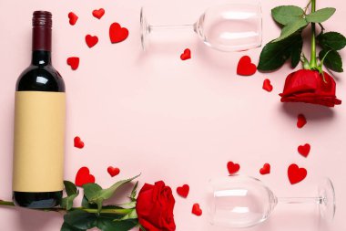 Frame made of wine bottle, glasses and rose flowers on pink background. Valentine's Day celebration