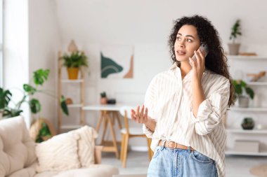 Young African-American woman talking by mobile phone at home