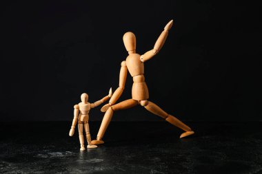 Wooden mannequins on dark background. Domestic violence concept