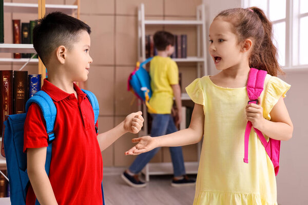 Cute little pupils with backpacks in library