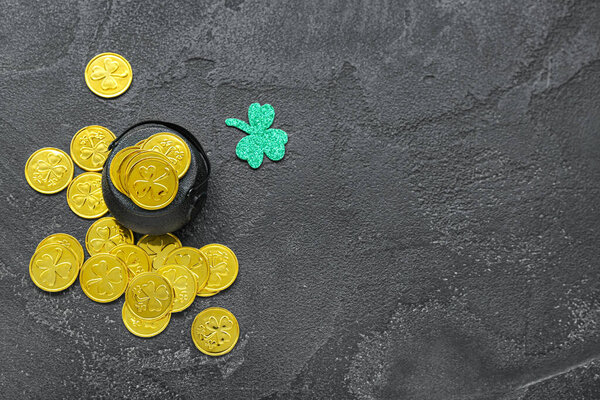 Pot with coins and paper clover on black grunge background. St. Patrick's Day celebration