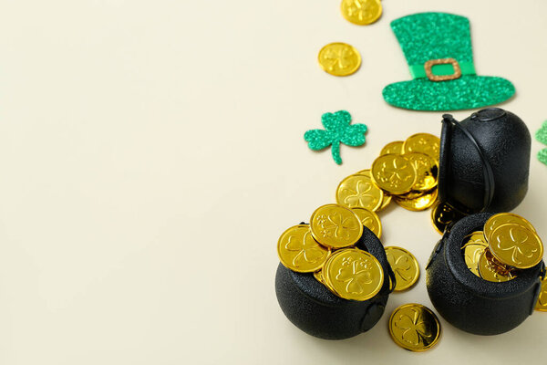 Pot with coins and paper decor on beige background. St. Patrick's Day celebration