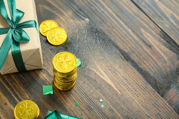 Stock image Gift with golden coins and sequins on brown wooden background. St. Patrick's Day celebration