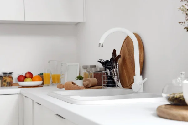 White counters with sink and utensils in interior of modern kitchen, closeup