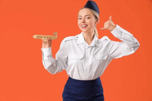 Young Stewardess Wooden Airplane Showing Call Gesture Orange Background — Φωτογραφία Αρχείου