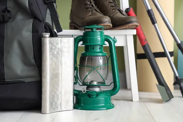Set of camping equipment with oil lantern and flask indoors, closeup