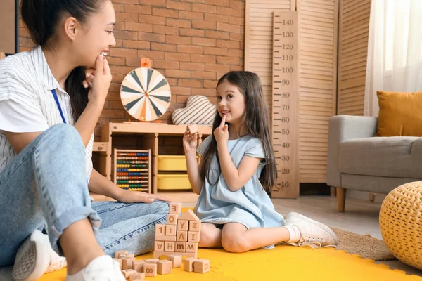 Female Asian speech therapist working with cute little girl in office