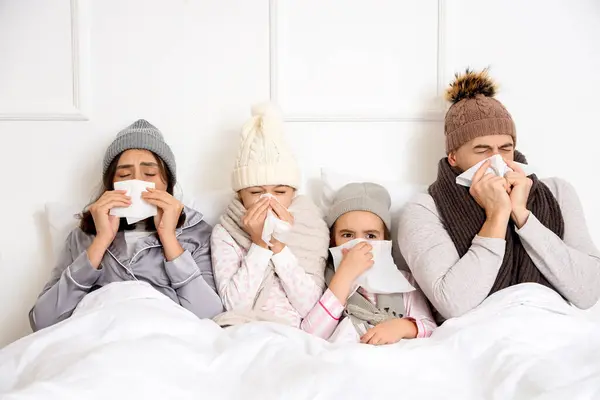 Ill family with tissues sneezing in bedroom
