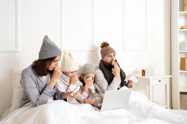 Ill family with laptop sneezing in bedroom