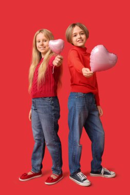Little children with heart-shaped balloons on red background. Valentine's Day celebration