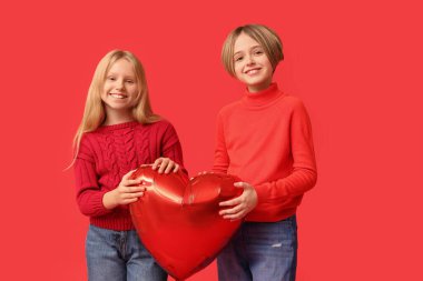 Little children with heart-shaped balloon on red background. Valentine's Day celebration