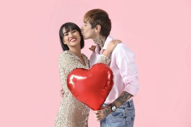 Young couple with balloon on pink background. Valentine's Day celebration