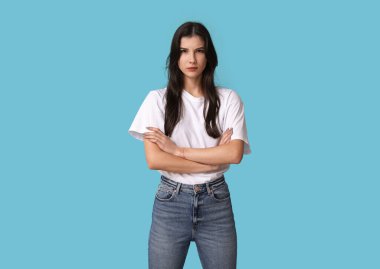 Young woman with crossed arms on blue background. Feminism concept