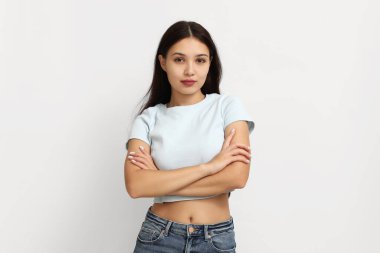 Young woman with crossed arms on white background. Feminism concept