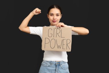 Young woman with sign GIRL POWER on black background. Feminism concept
