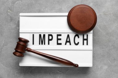 Judge gavel and board with word IMPEACH on grey grunge background