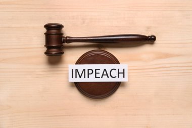 Judge gavel with word IMPEACH on wooden background