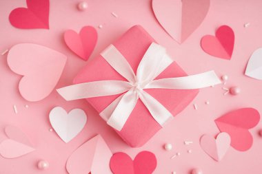Gift box with paper hearts and decor on pink background. Valentine's Day celebration