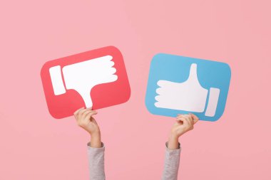 Little girl with like and dislike icons on pink background