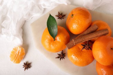 Board of sweet mandarins with star anise and cinnamon on white background