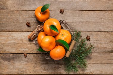 Basket of sweet mandarins with cinnamon, star anise and fir branches on wooden background