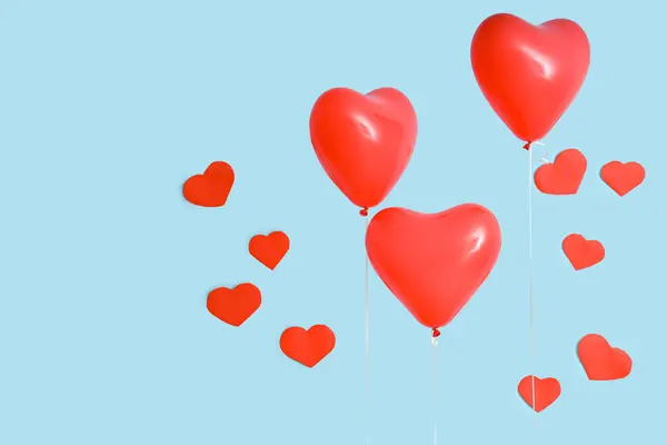 Heart-shaped balloons and paper hearts on blue background. Valentine\'s Day celebration