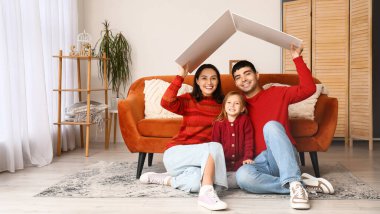 Happy family with cardboard dreaming about their new house at home