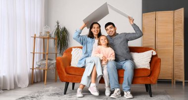 Happy family with cardboard dreaming about their new house at home