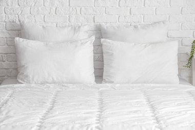 Yatak odasının içinde beyaz battaniyeli ve yastıklı rahat bir yatak.