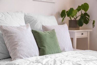 Beyaz battaniyeli rahat bir yatak ve hafif yatak odasında yastıklar.