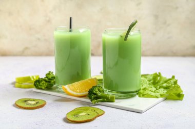 Glasses of tasty juice with fresh vegetables and fruits on table