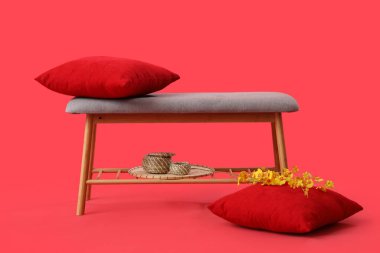 Grey bench with cushions and flowers on red background