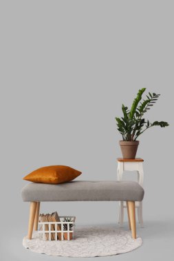 Yastıklı bank ve gri arka planda ev bitkisi