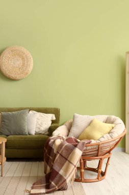 Cozy armchair with blanket and cushions in interior of stylish living room