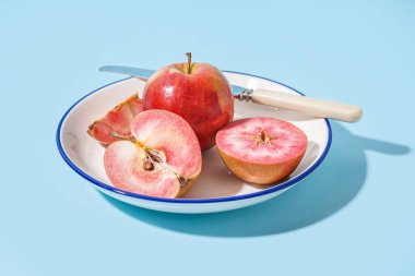Plate with sweet pink apples on blue background