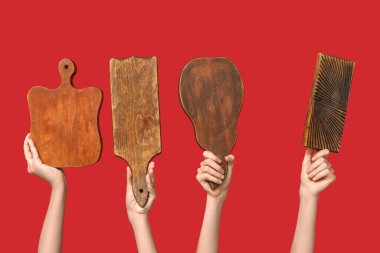 Female hands with wooden cutting boards on red background