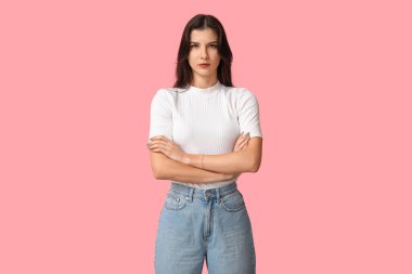 Confident young woman with crossed arms on pink background. Feminism concept