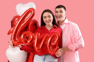 Young couple with word LOVE made of balloons on pink background. Valentine's Day celebration