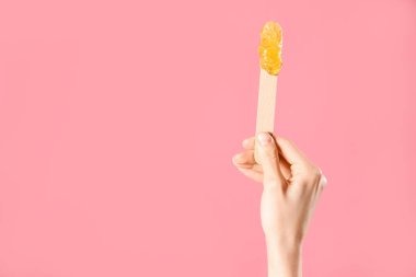 El ele tutuşma spatulası ve pembe arka planda şekerleme macunu.