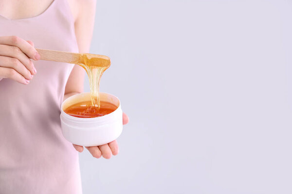 Woman with sugaring paste on light background, closeup