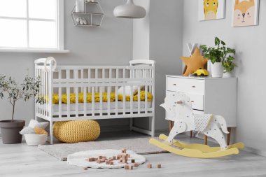 Bebek beşiği, oyuncakları ve tuvaleti olan aydınlık yatak odasının içinde.