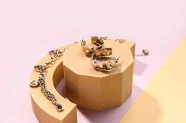 Gümüş küpeli dekoratif podyumlar ve renk arkaplanlı bilezikler