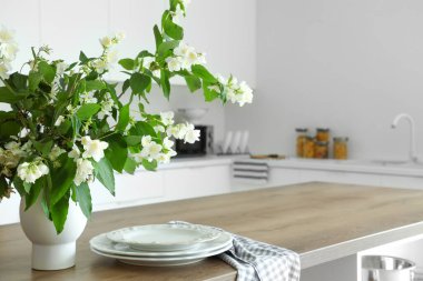 Modern mutfaktaki ahşap masada yasemin çiçekleri açan vazo.