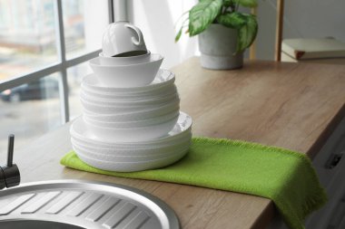 Stack of clean dishes on wooden counter in modern kitchen, closeup