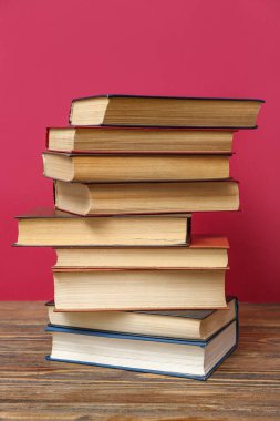 Kırmızı arkaplana karşı ahşap masadaki kitap yığını