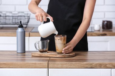 Bayan barista mutfaktaki ahşap masada lezzetli bir kahve hazırlıyor.