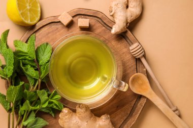Kahverengi zemin üzerinde limon ve nane aromalı bir bardak zencefil çayı.